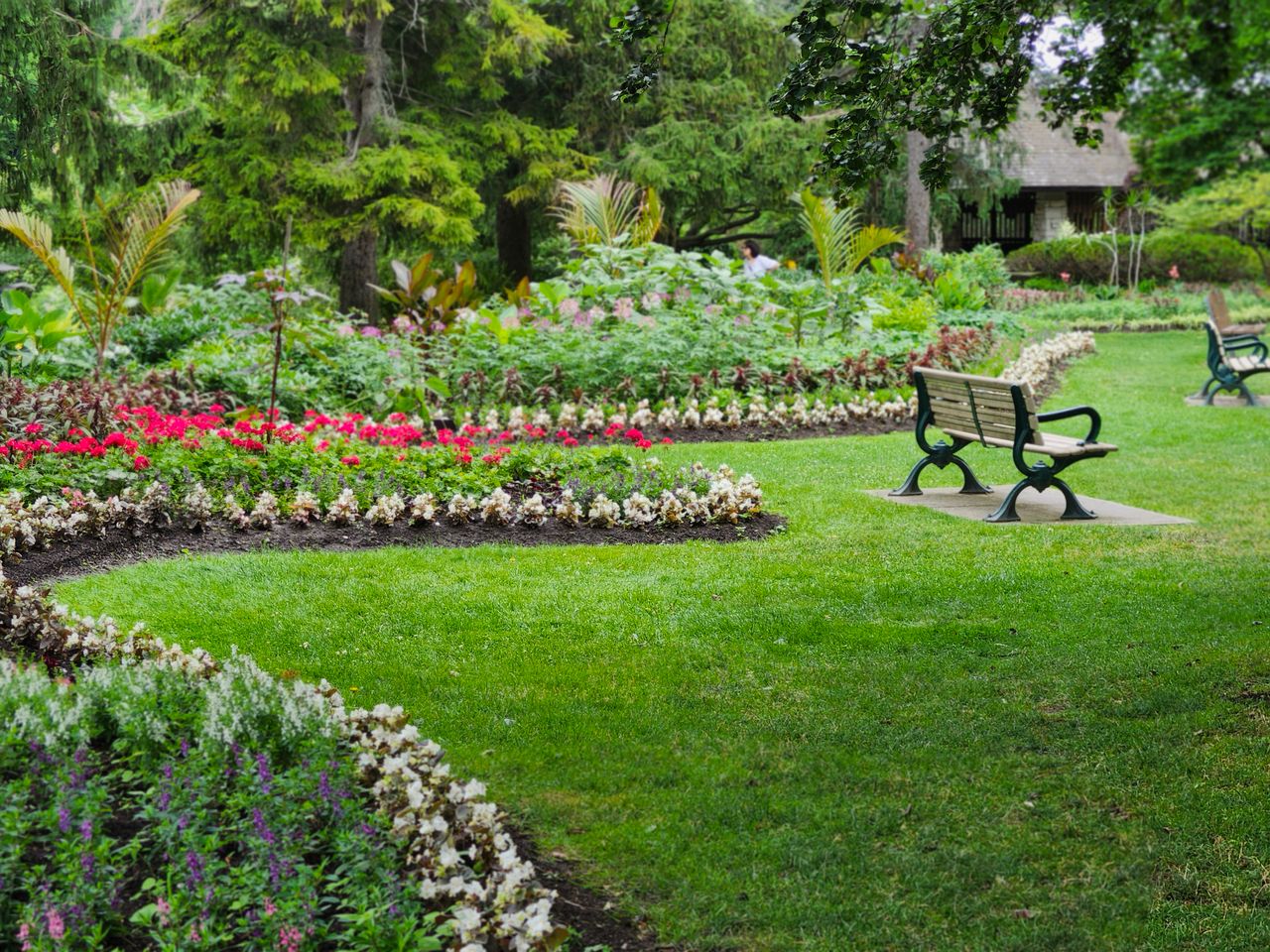 Beautiful garden with benches and vibrant flowers in a Toronto park during the day.