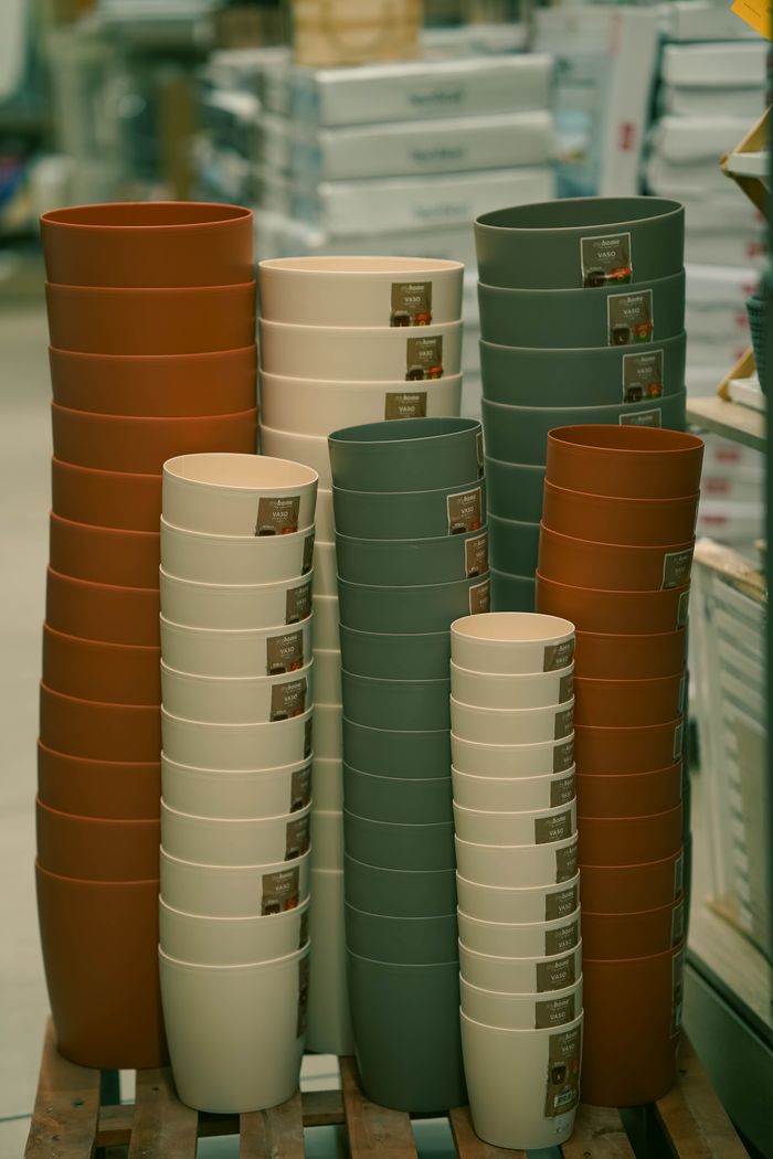 Neatly stacked flower pots of various colors in a hardware store aisle.